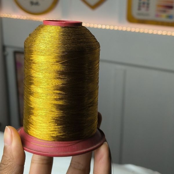 Linha metálica dourada em uso no bordado