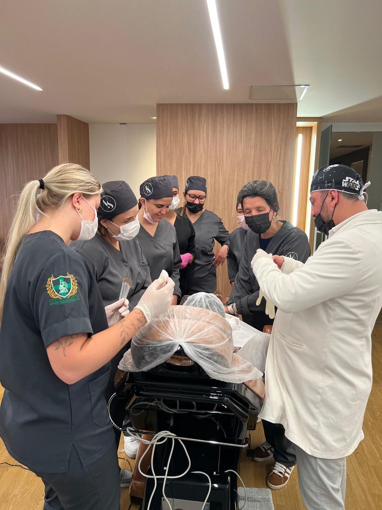Dr. Schalins em prática clínica demonstrando procedimentos em paciente para os alunos
